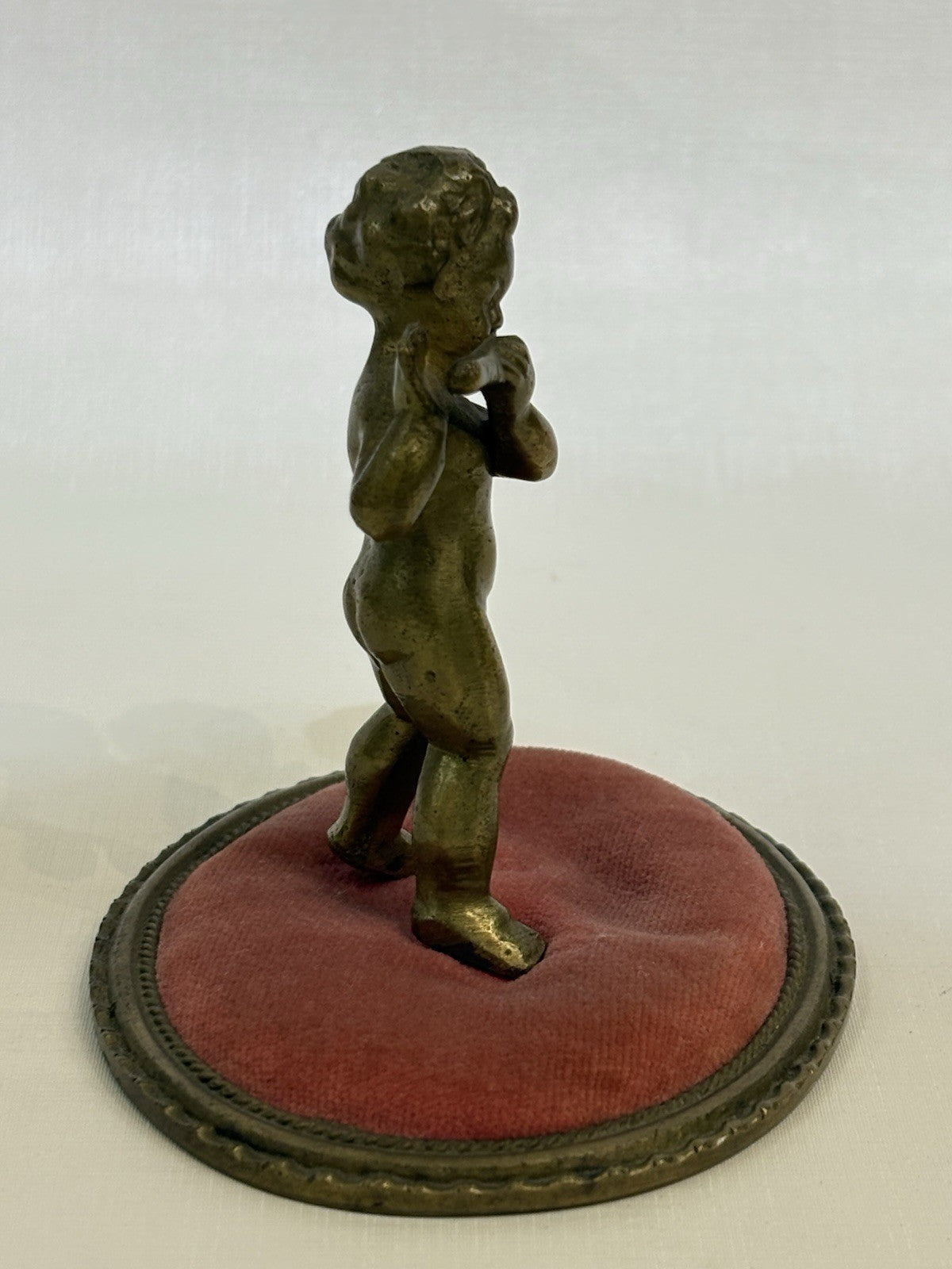 ntique pincushion featuring a small bronze figure of a child playing a flute