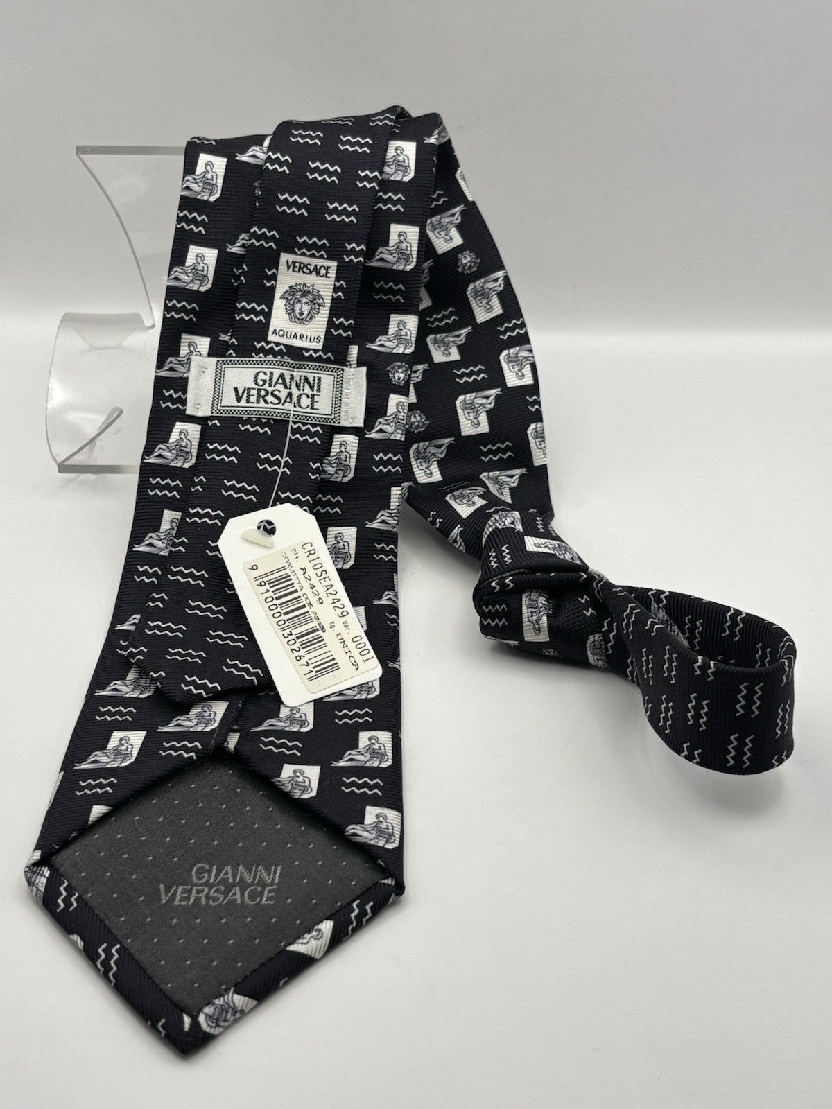 Versace necktie black background with a white graphic print Medusa head logo.