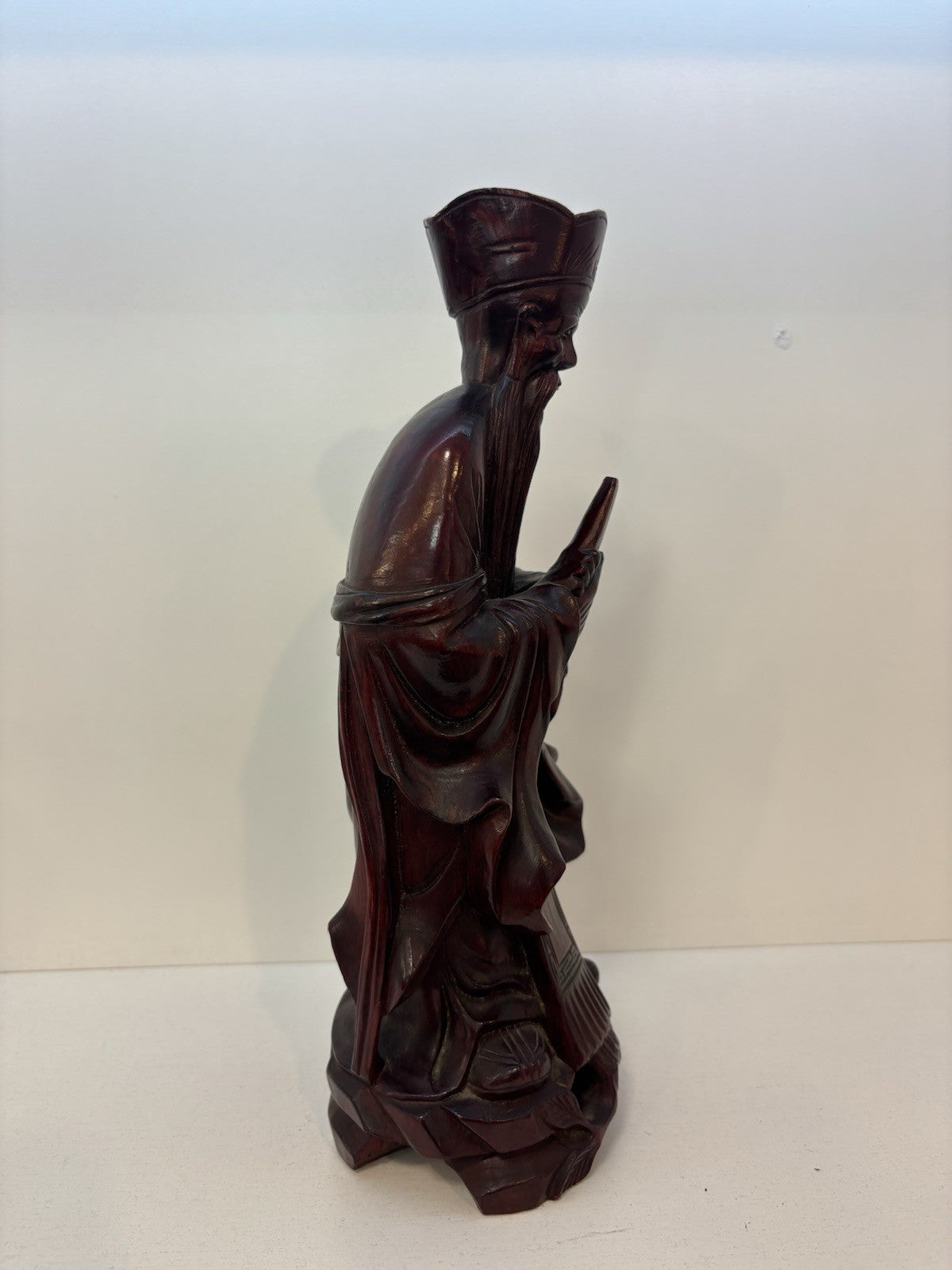 The statue is a carved wooden figurine of the Chinese deity Wenchang Wang.