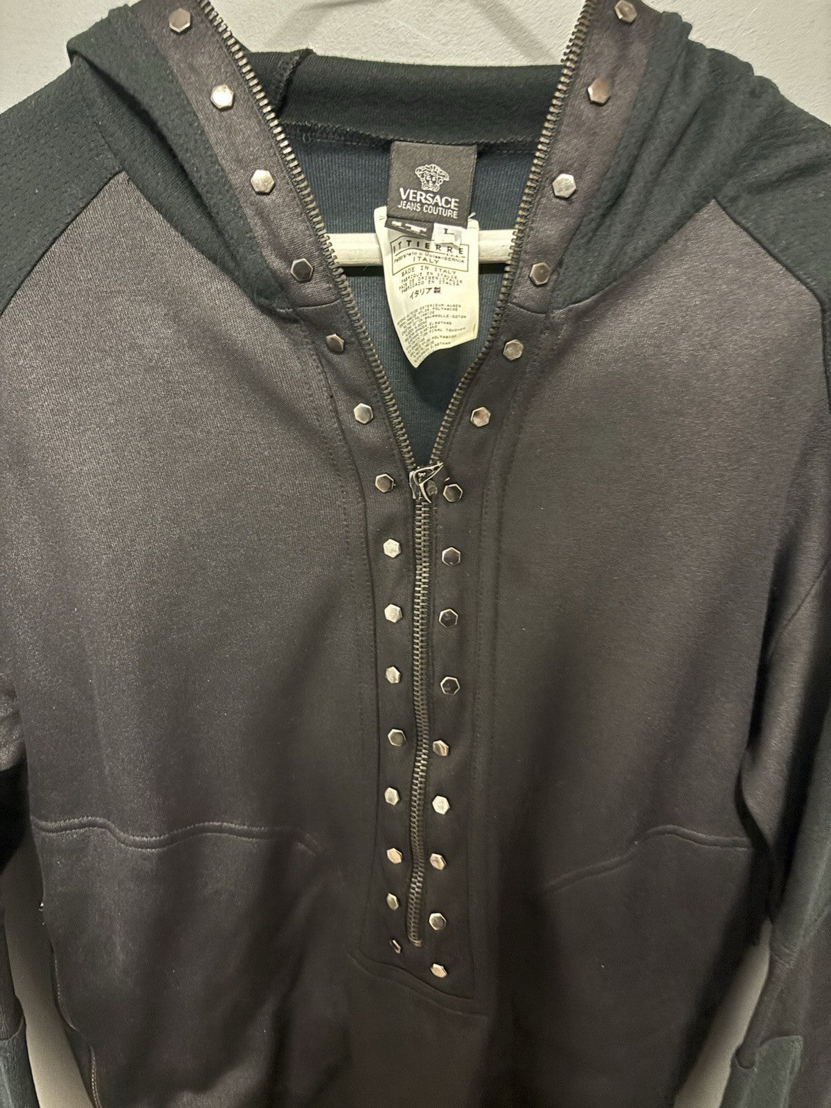 Black Versace hoodie with a half-zip and stud details.