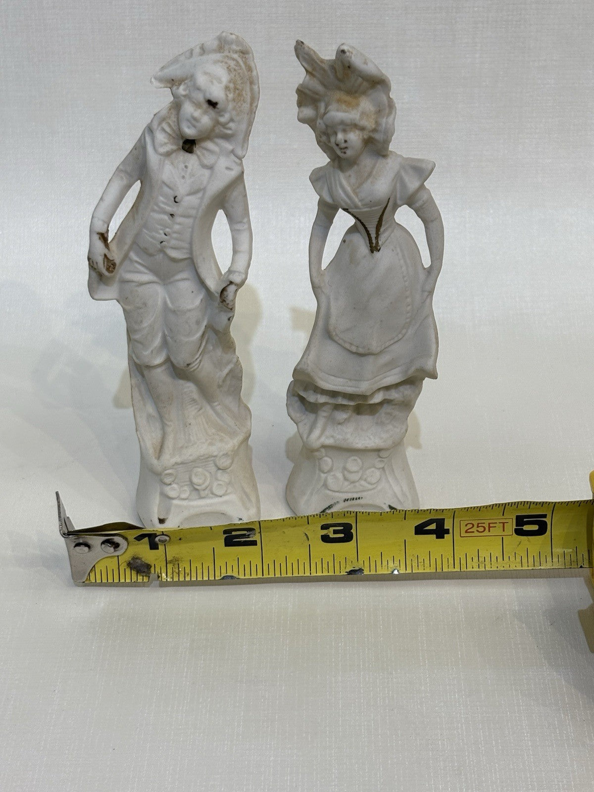 pair of vintage bisque porcelain figurines depicting a Victorian style couple