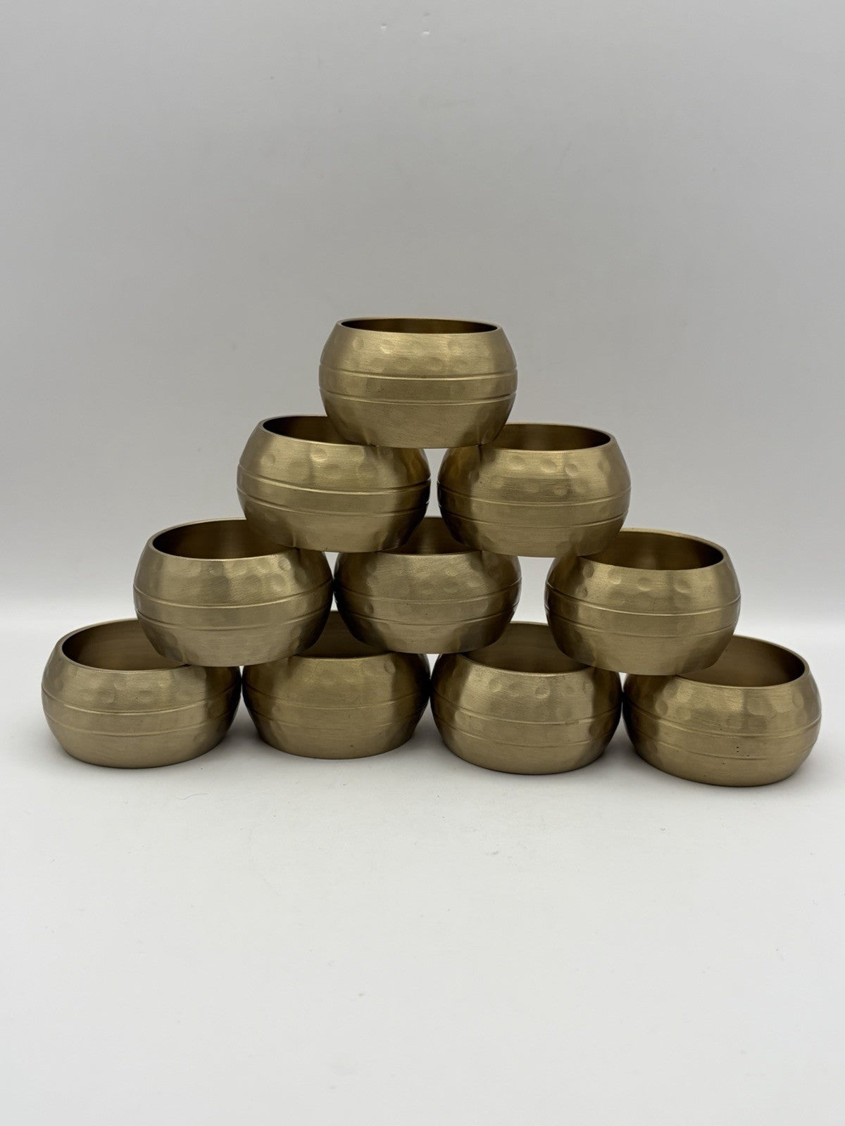 vintage or late 20th-century hammered brass napkin rings, often sold in sets.