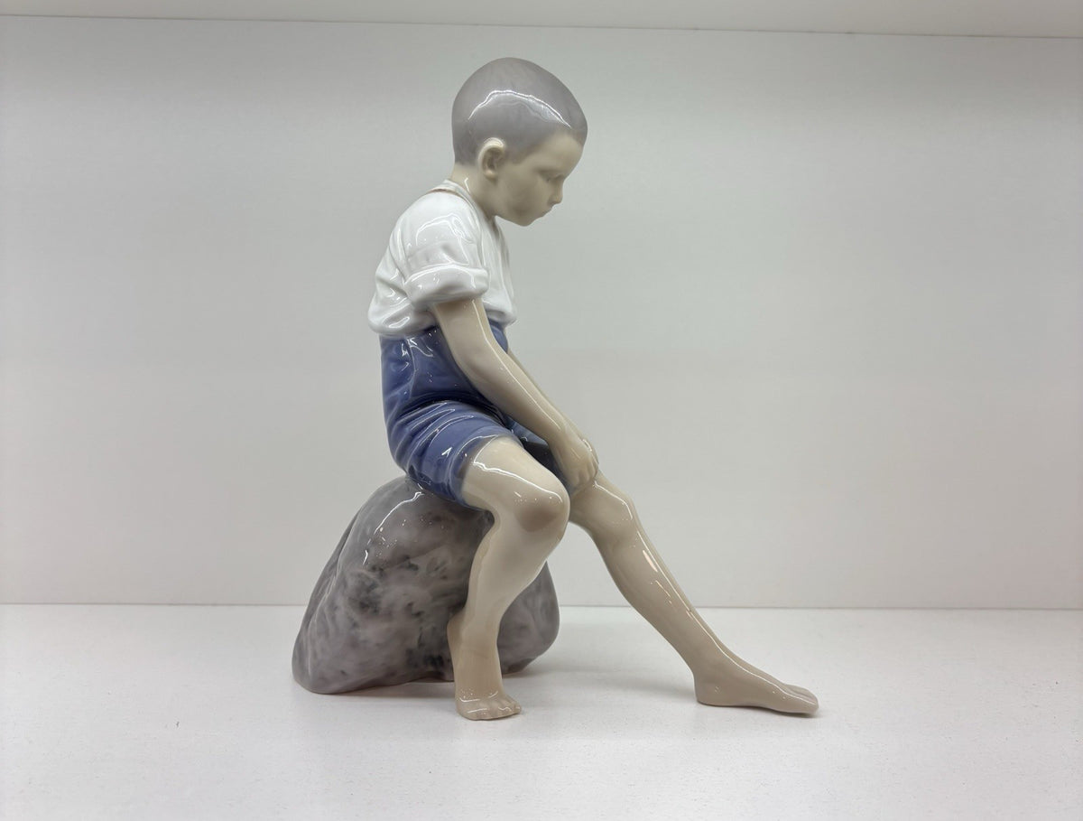 Bing & Grondahl Boy sitting on stone rolling up trousers