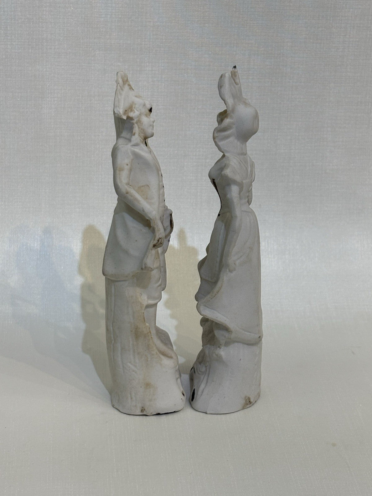 pair of vintage bisque porcelain figurines depicting a Victorian style couple