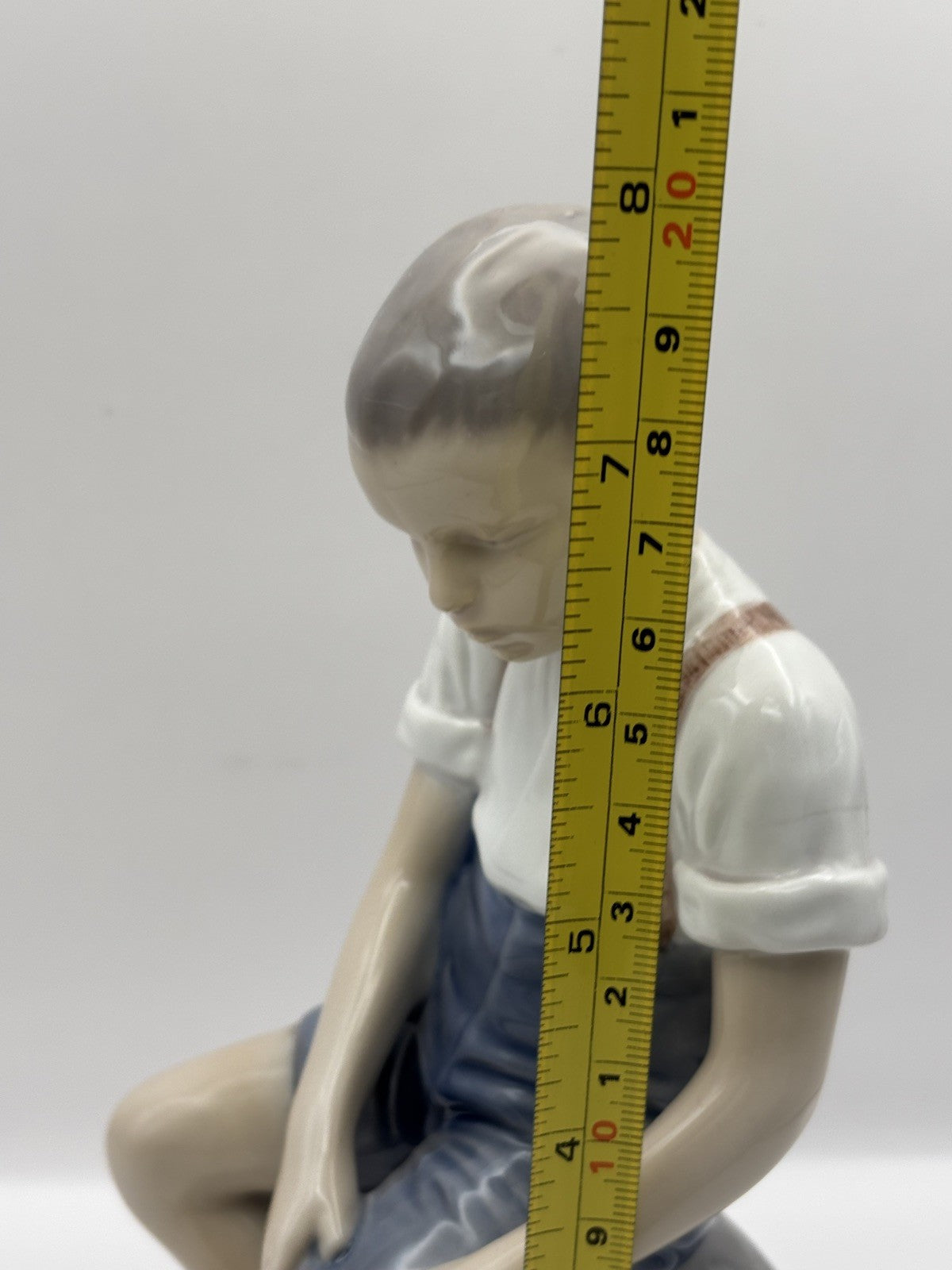 Bing & Grondahl Boy sitting on stone rolling up trousers