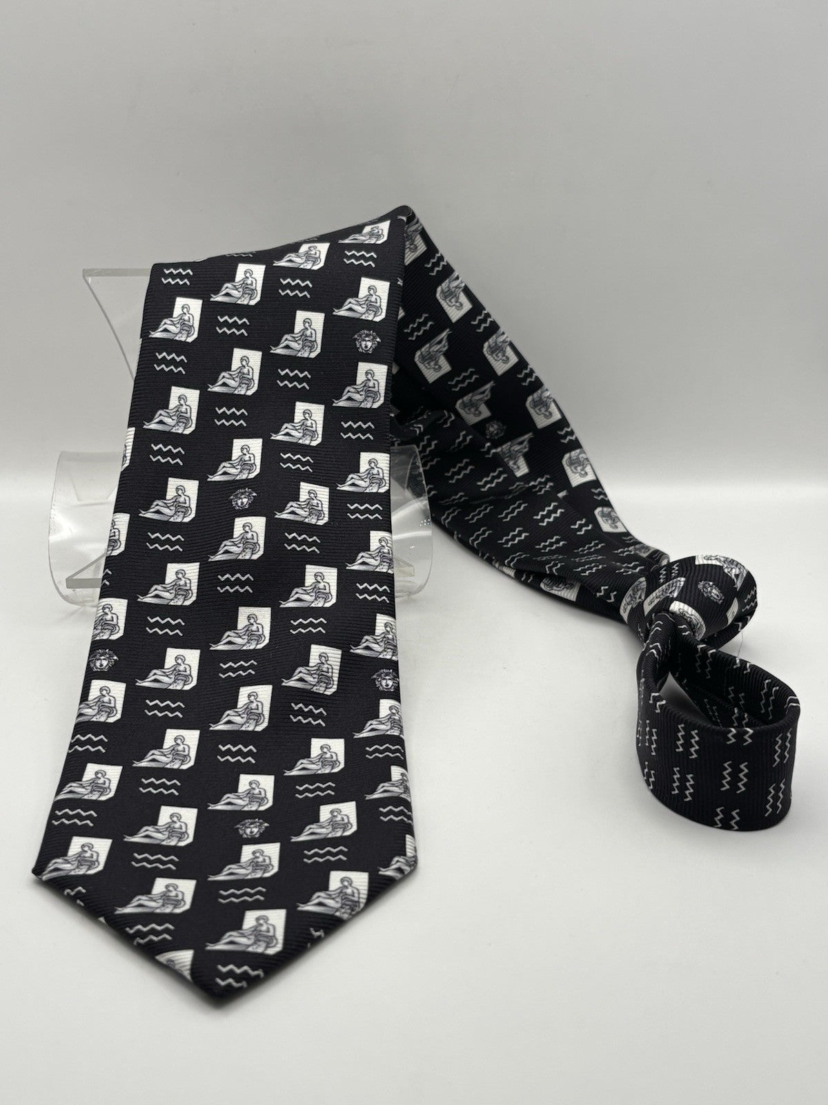 Versace necktie black background with a white graphic print Medusa head logo.