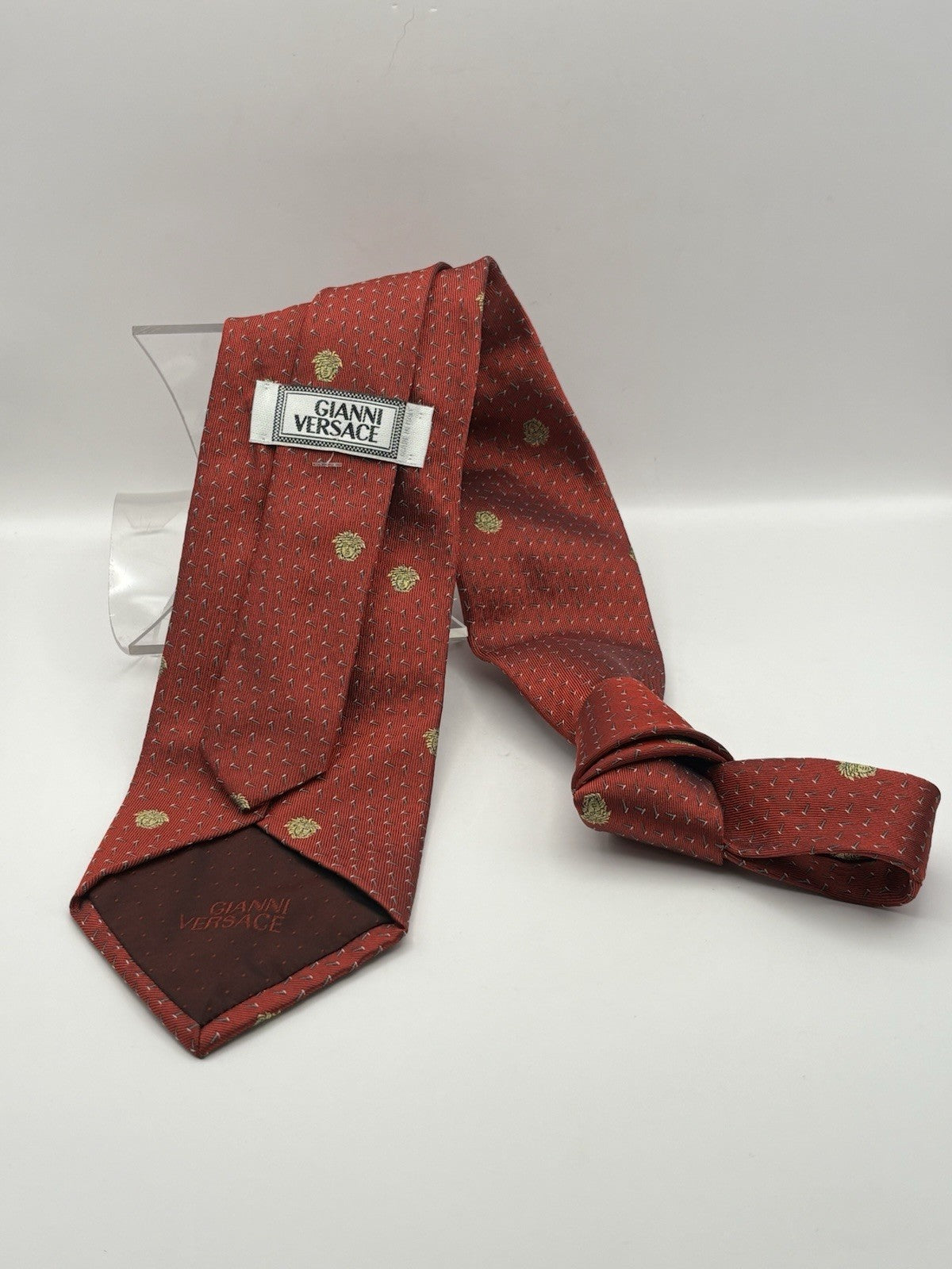 Vintage Gianni Versace red silk tie featuring a golden Medusa head pattern.