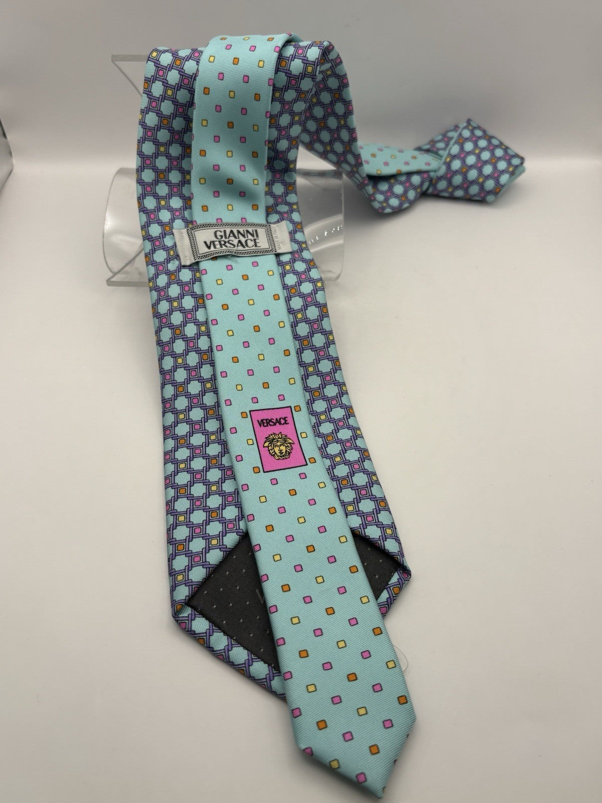 Gianni Versace tie light blue color palette prominent gold Medusa emblem.