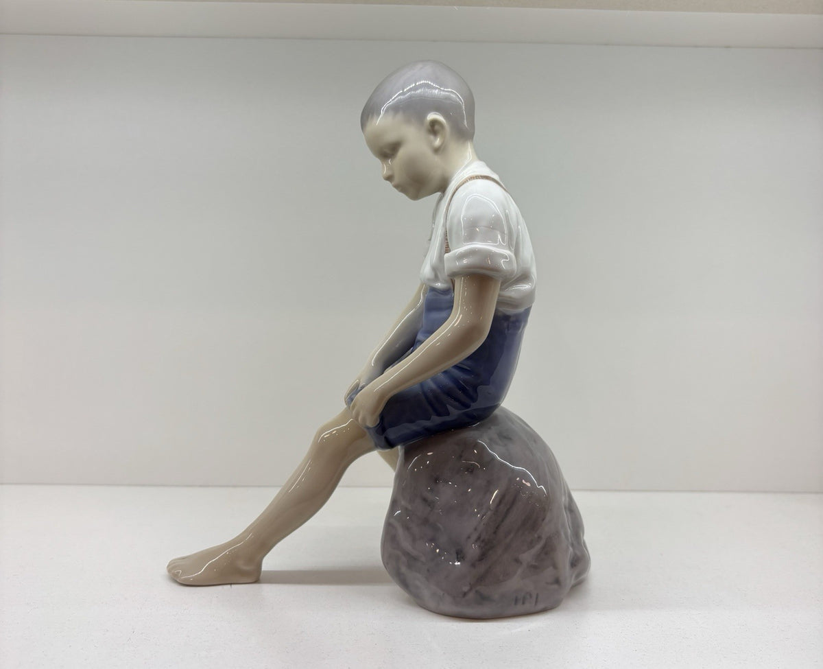 Bing & Grondahl Boy sitting on stone rolling up trousers