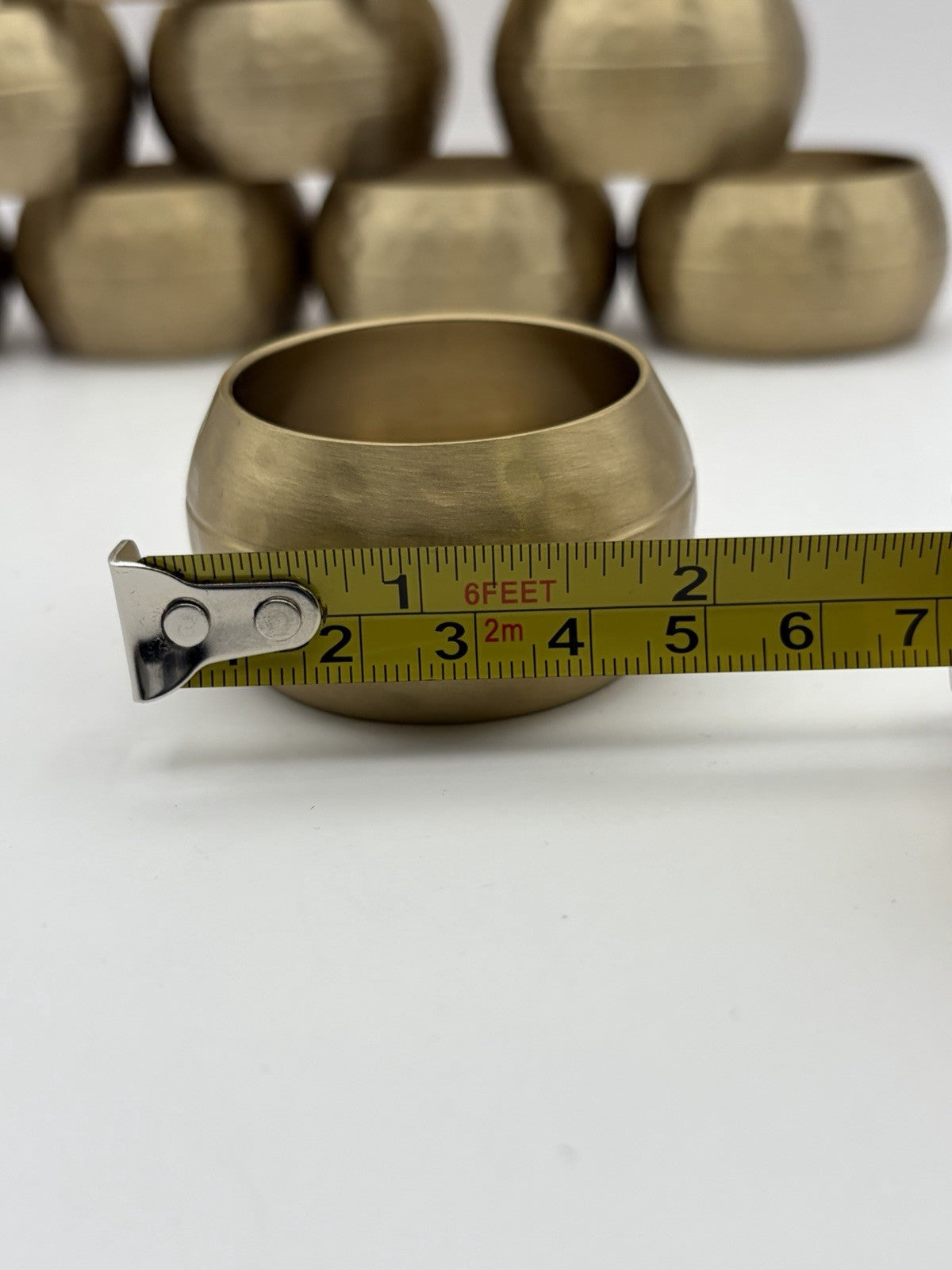 vintage or late 20th-century hammered brass napkin rings, often sold in sets.