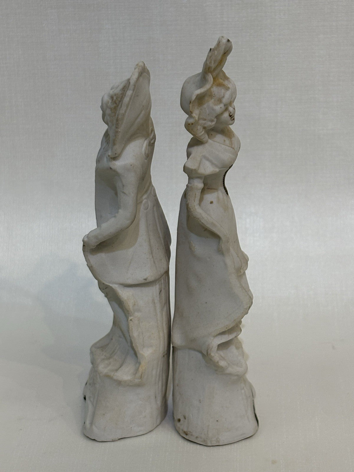 pair of vintage bisque porcelain figurines depicting a Victorian style couple