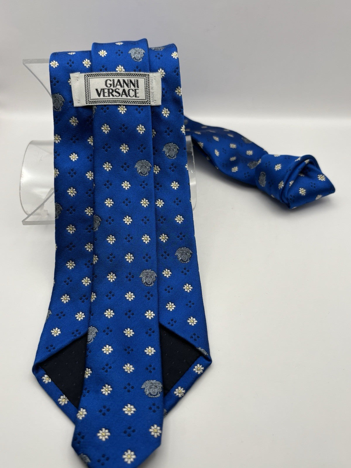 Versace tie vibrant blue silk Medusa head emblems and delicate floral patterns.