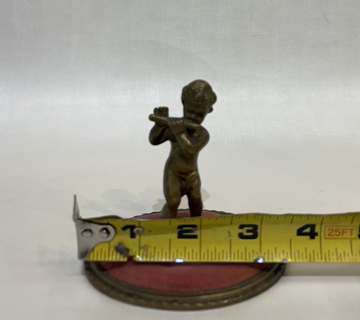 ntique pincushion featuring a small bronze figure of a child playing a flute