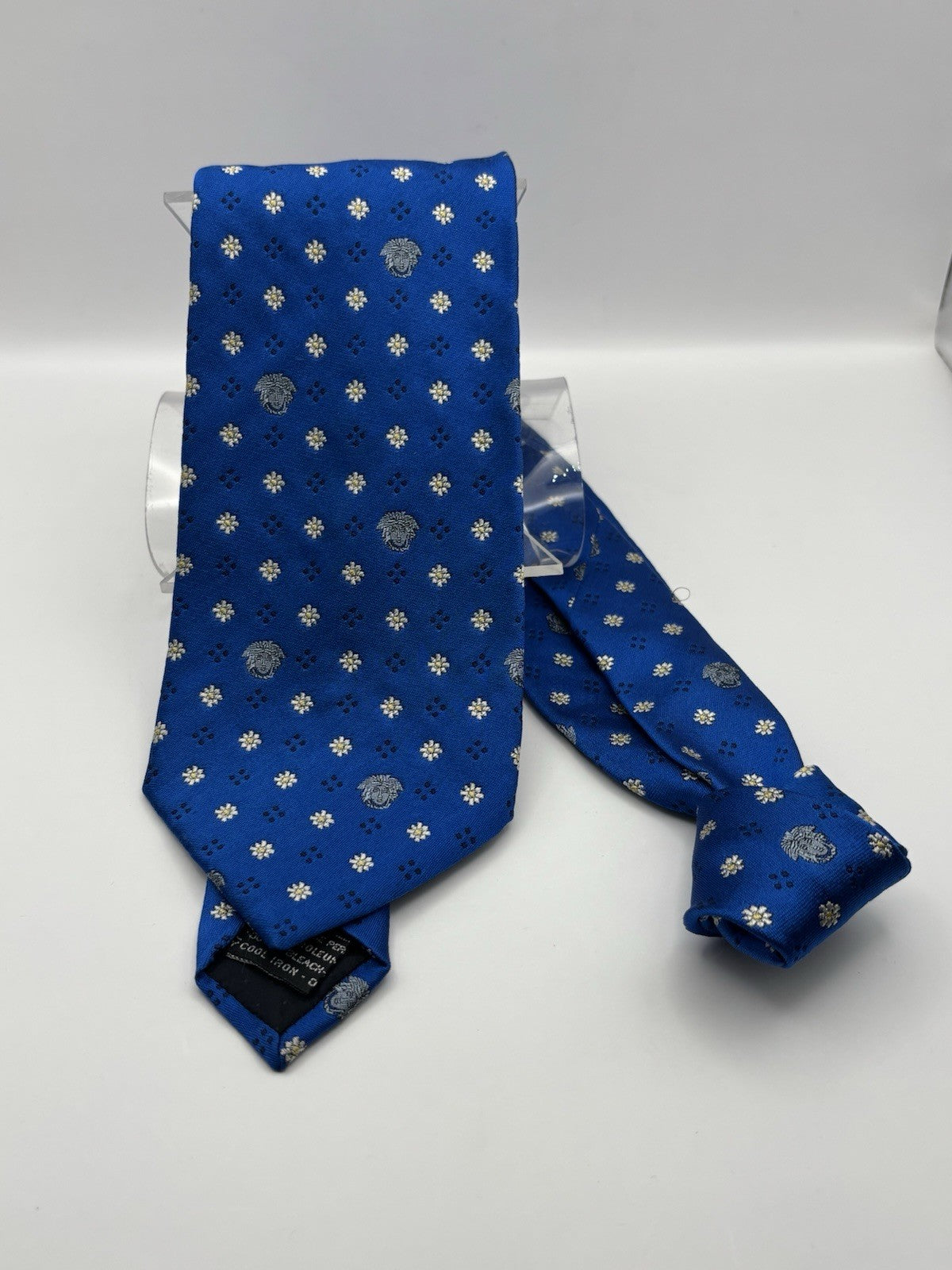 Versace tie vibrant blue silk Medusa head emblems and delicate floral patterns.