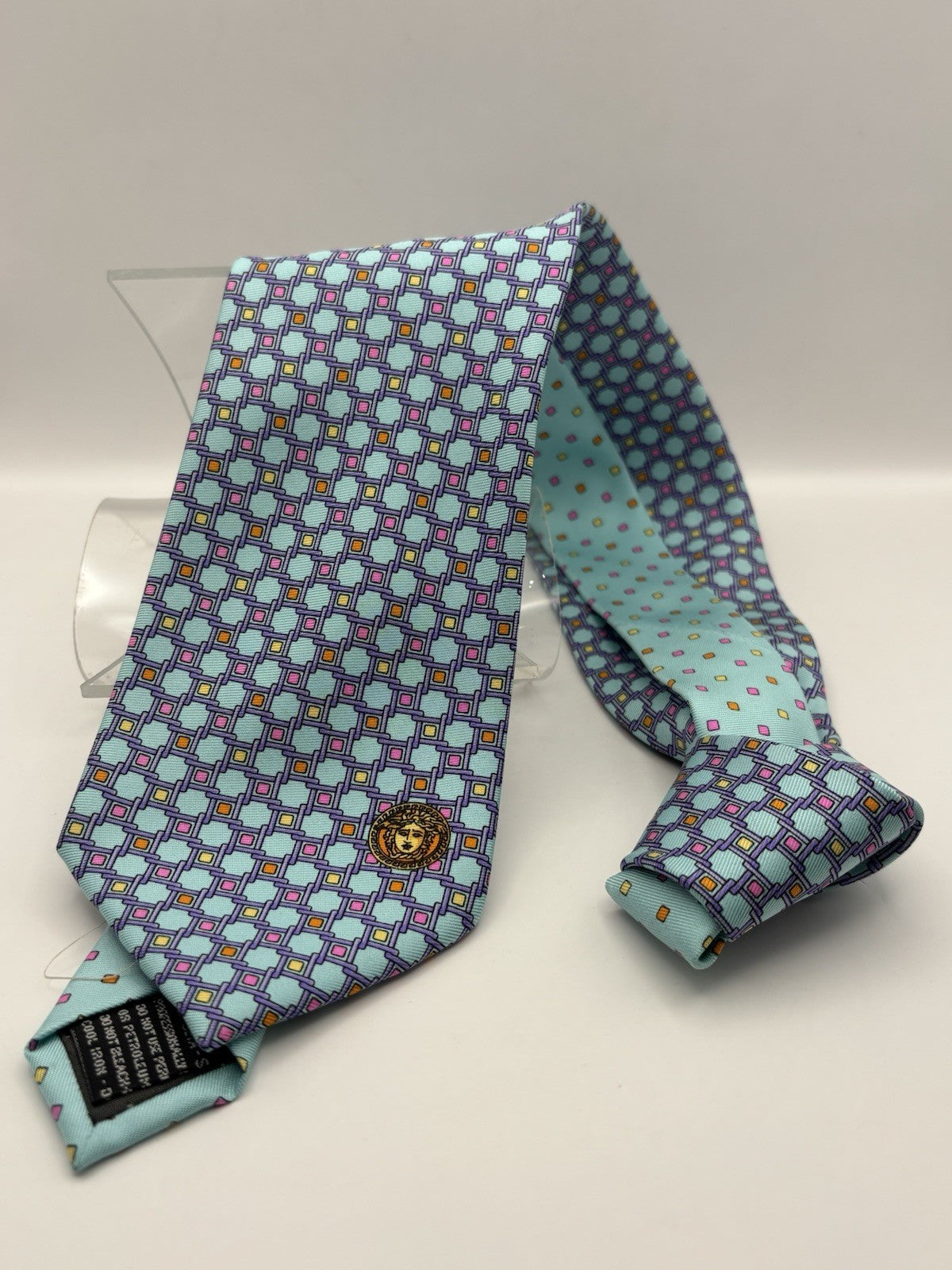 Gianni Versace tie light blue color palette prominent gold Medusa emblem.