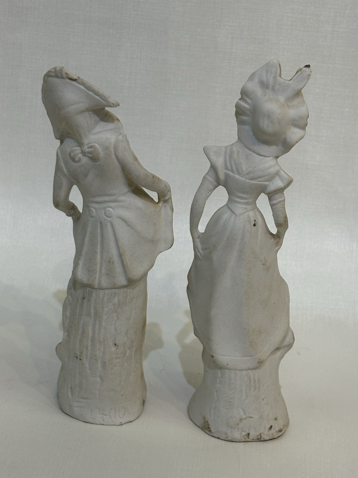 pair of vintage bisque porcelain figurines depicting a Victorian style couple