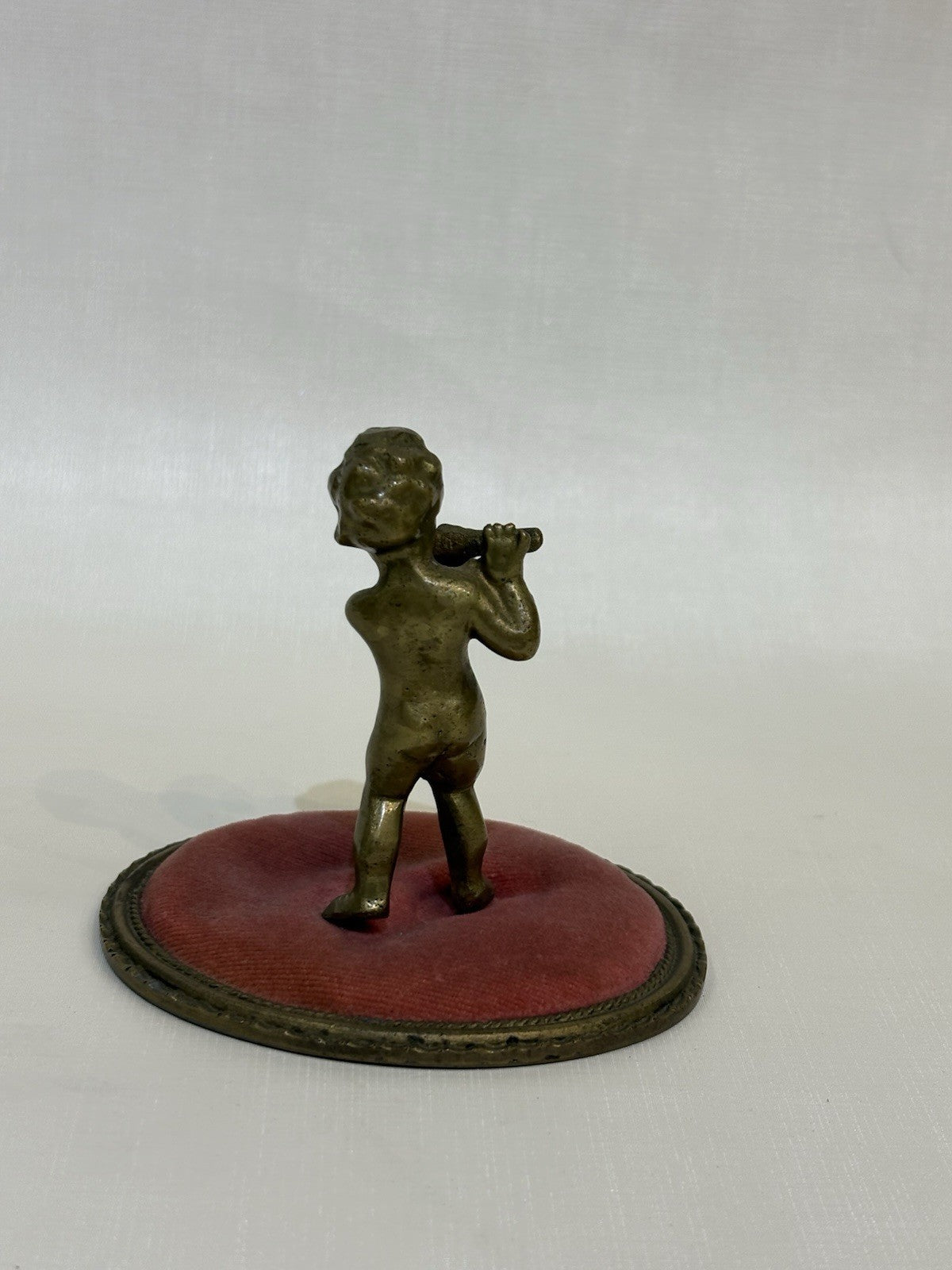 ntique pincushion featuring a small bronze figure of a child playing a flute